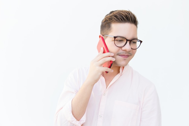 Pensive guy in eyeglasses speaking on cell and looking away