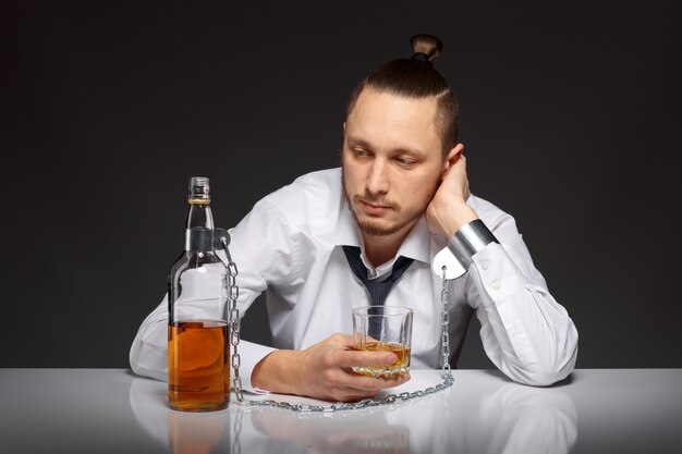 Pensive guy holding a glass of whiskey