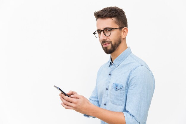 Pensive guy using smartphone, texting message