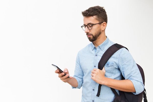 Ragazzo pensieroso con zaino utilizzando smartphone