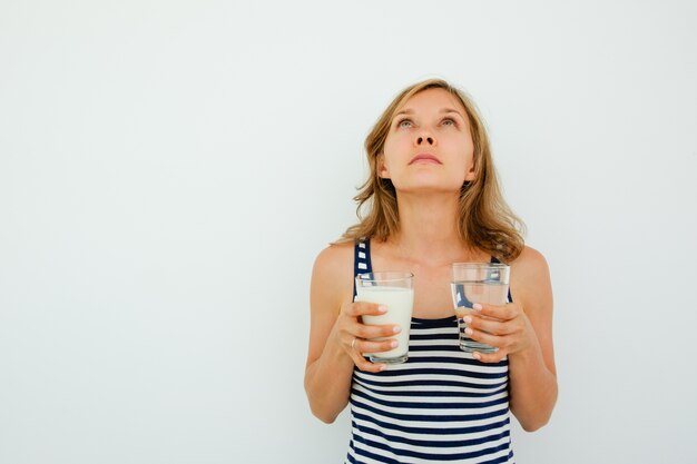 Pensive Lady Holding Glasses of Water and Milk