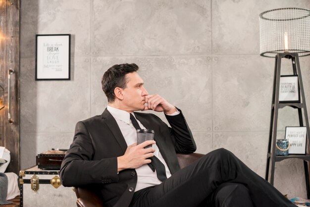 Pensive man holding cup of coffee in room