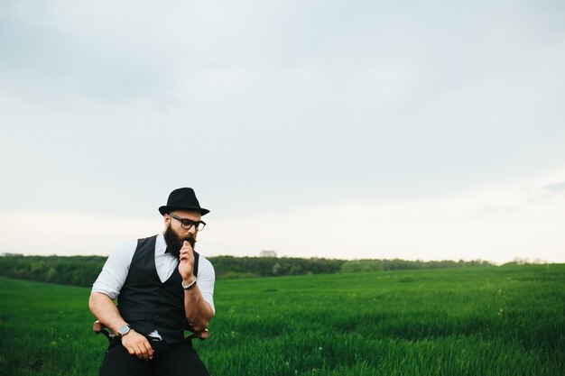 Pensive man with hat sitting outdoors