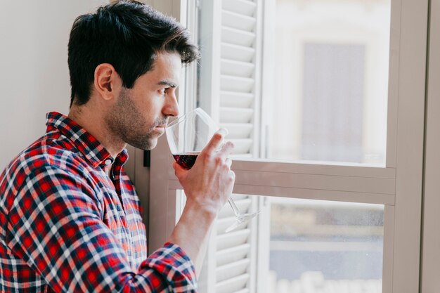 Pensive man with wine at window