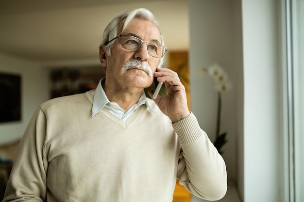 Pensive mature man communicating with someone over mobile phone