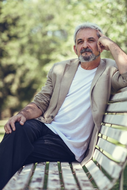 Free Photo | Pensive mature man sitting on bench in an urban park.