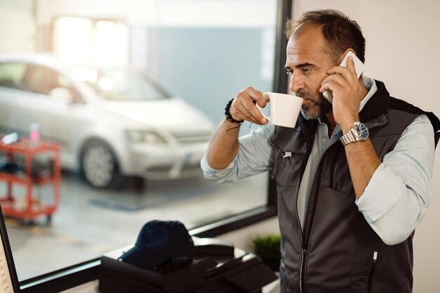 オフィスでコーヒーブレイクをしながら電話で話している物思いにふけるメカニック