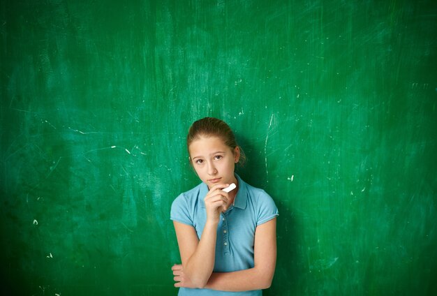 Pensive schoolgirl with blackboard background