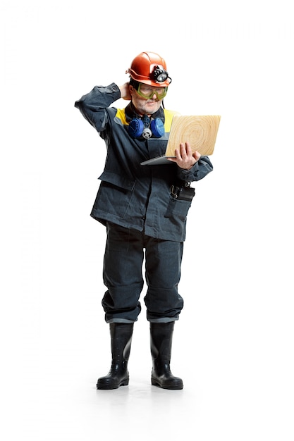 pensive senior bearded male miner standing at the camera with laptop on a white