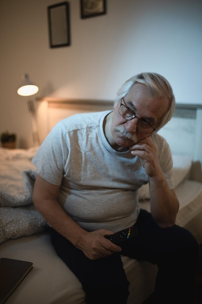 Free photo pensive senior man thinking of something while sitting awake late at night in bedroom