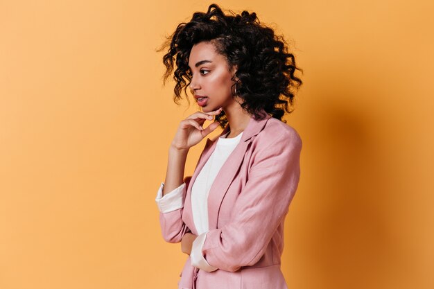 Pensive sensual woman posing on yellow wall