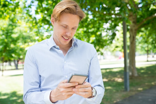 Pensive smiling guy texting message on phone