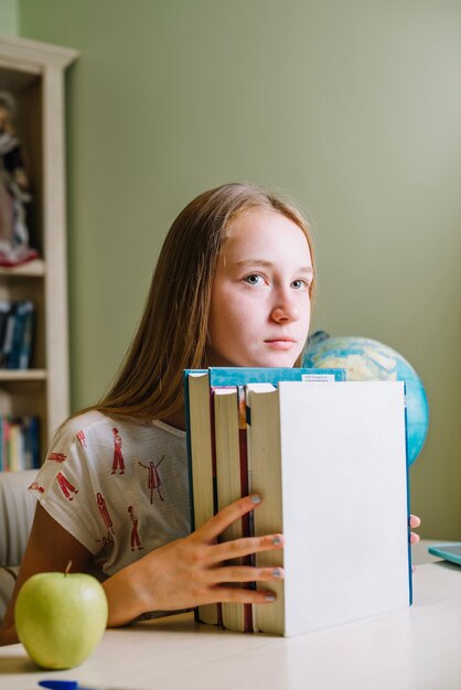 積み重なった本を持った少人数の学生