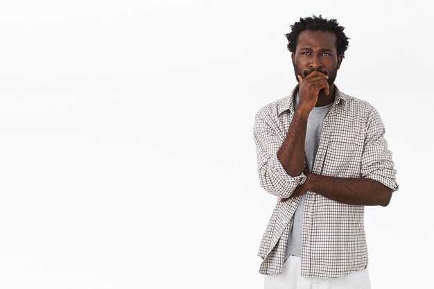 Pensive and unsure, thoughtful african-american man, touching beard, frowning and looking up