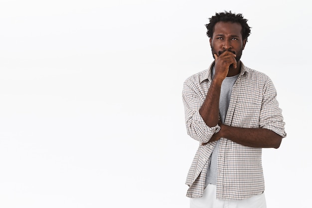 Pensive and unsure, thoughtful african-american man, touching beard, frowning and looking up