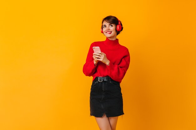 Pensive woman in black skirt holding smartphone