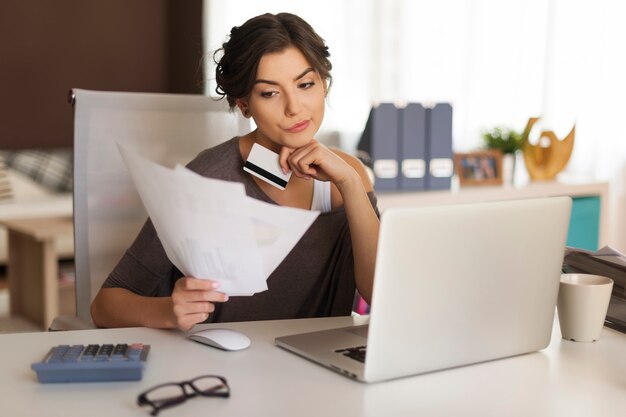 Pensive woman paying bills at home