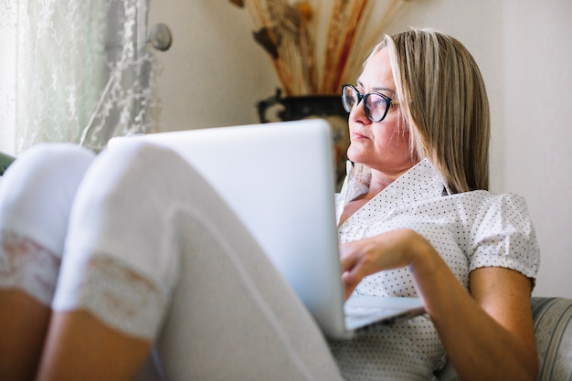 Free photo pensive woman resting with laptop on sofa