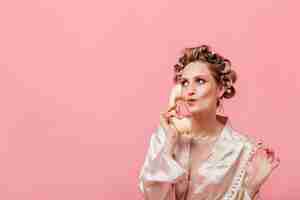 Free photo pensive woman in silk robe talking on phone on isolated wall