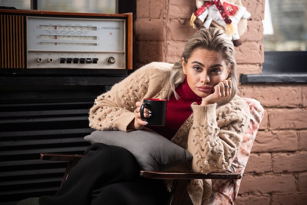 Pensive woman sitting and reading book and drinking coffee