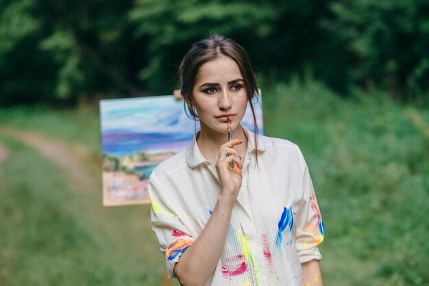 Pensive woman with a paintbrush in her mouth