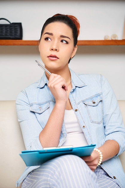 Pensive woman working on sofa