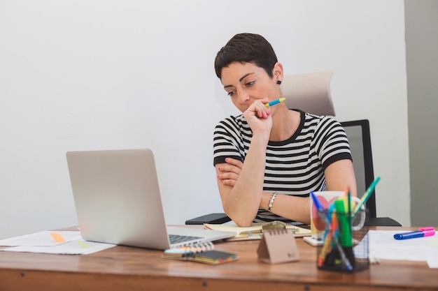 Pensive worker with right hand next to her mouth