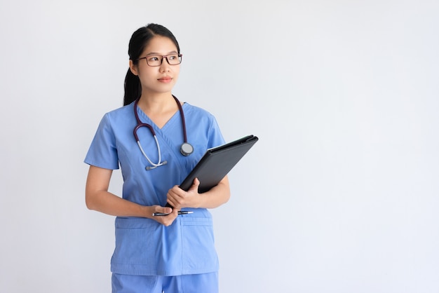 Задумчивый молодой азиатский женский доктор держа документы