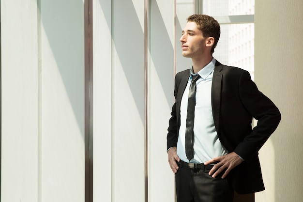 Free photo pensive young businessman looking out window