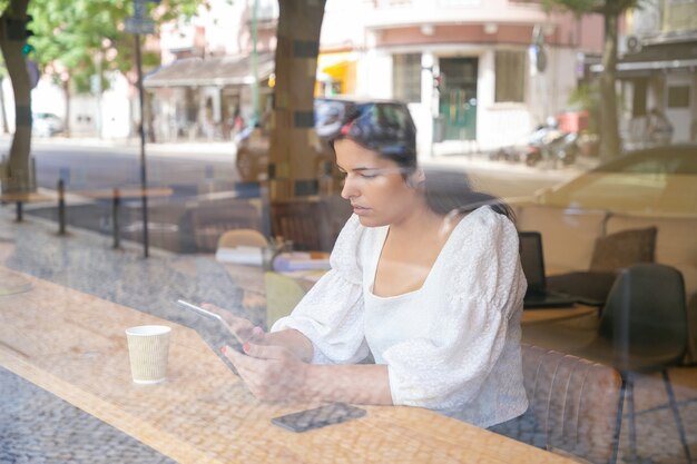 タブレットを使用して、コワーキングスペースやコーヒーショップの机に座っている物思いにふける若い実業家