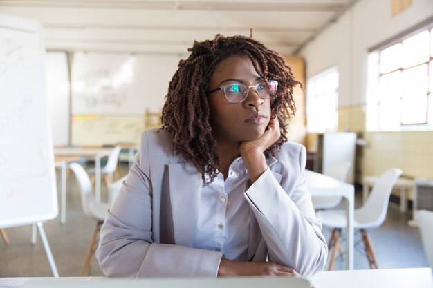 Pensive young businesswoman sitting in office