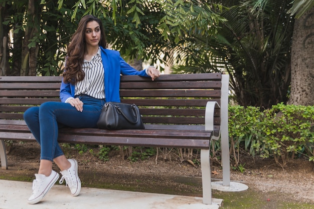 Pensive young businesswoman sitting in the park