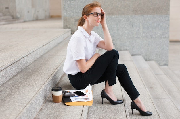 Free photo pensive young businesswoman sitting on staircase