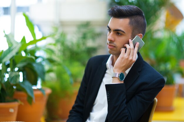 Задумчивый молодой предприниматель разговаривает по телефону