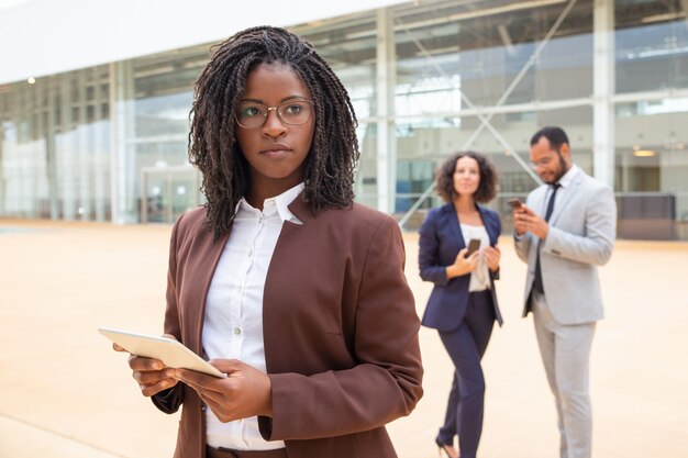 Pensive young female employee using tablet outside