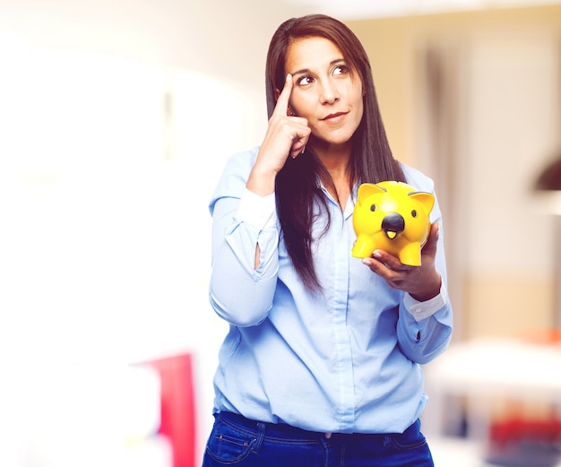 Free photo pensive young lady holding a yellow piggybank