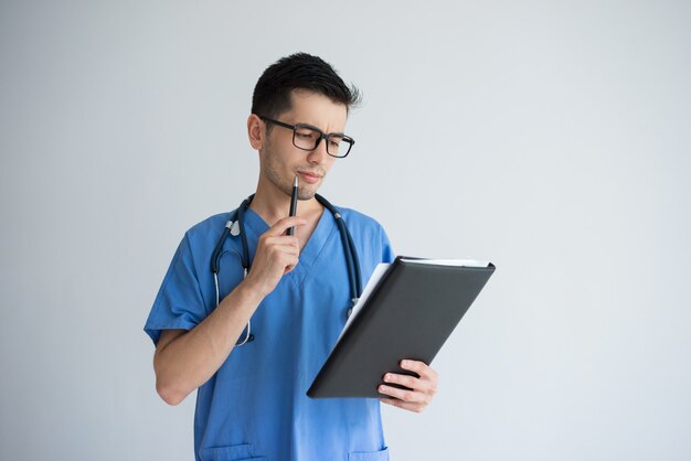 Pensive young male doctor writing medical prescription. Doctor occupation concept