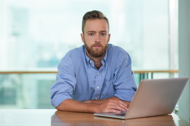 カフェ表でノートパソコンでの作業物思い若い男性