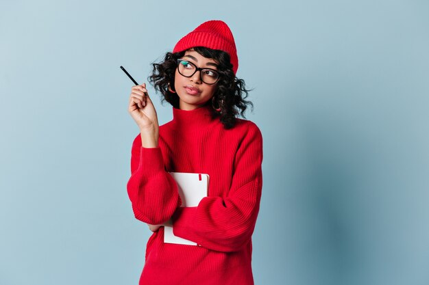 Pensive young woman in glasses and red hat looking away