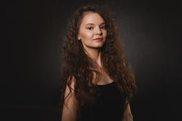 People, beauty and lifestyle concept. Isolated shot of mysterious young female with black eyes and voluminous dark hair