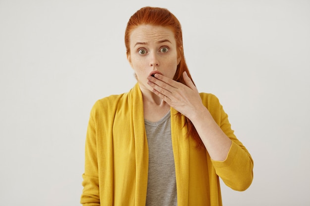 People, body language and facial expressions concept. Beautiful redhead female covering mouth with hand