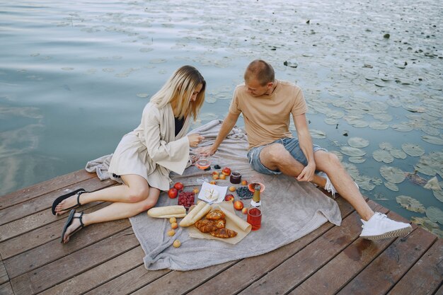 People by the river. Delicious healthy summer picnic on the grass. Fruits on a blancet.