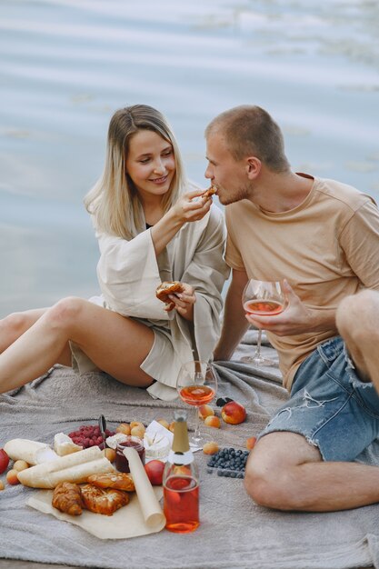 People by the river. Delicious healthy summer picnic on the grass. Fruits on a blancet.