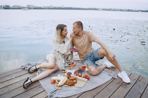 People by the river. Delicious healthy summer picnic on the grass. Fruits on a blancet.