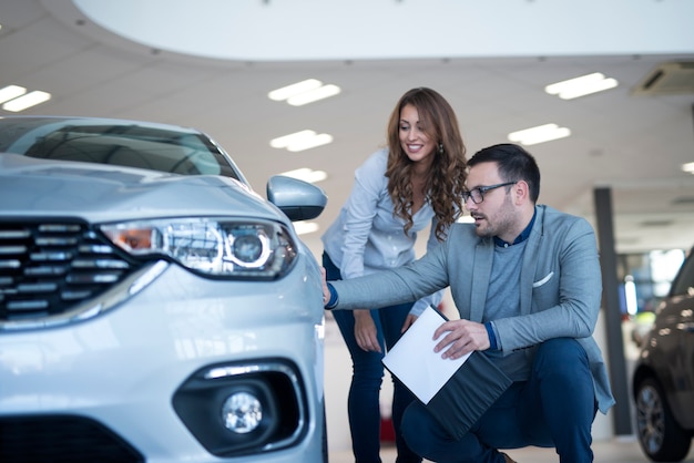 Persone nello showroom di concessionaria auto discutendo di nuovo veicolo