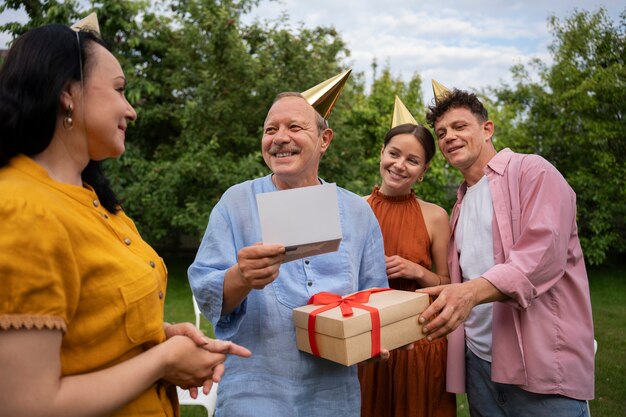 高齢者の誕生日パーティーを庭で屋外で祝う人々