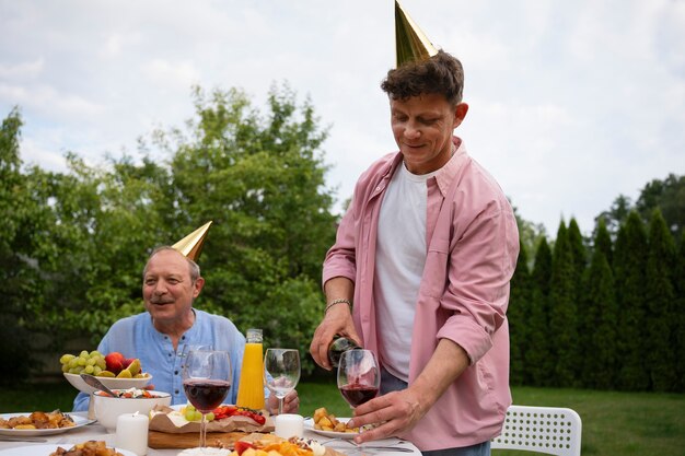 高齢者の誕生日パーティーを庭で屋外で祝う人々