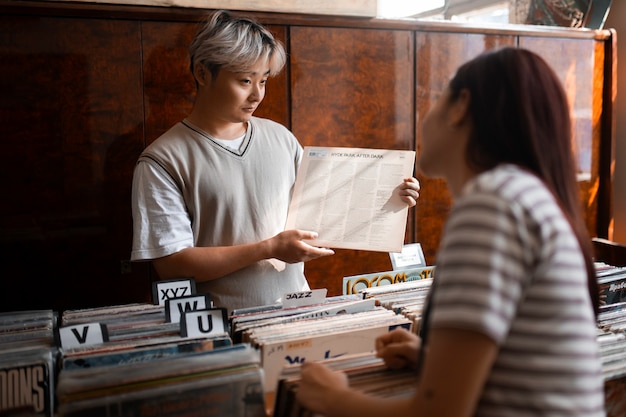 Free photo people checking vinyl records at shop side view