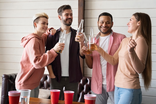 Foto gratuita persone che applaudono e bevono birra mentre giocano a beer pong a una festa al coperto