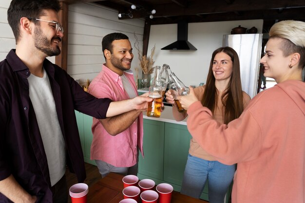 People cheering and drinking beer while playing beer pong at an indoor party